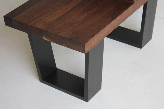Close-up of the End Table's black metal leg base and walnut top edge, showing the joinery detail