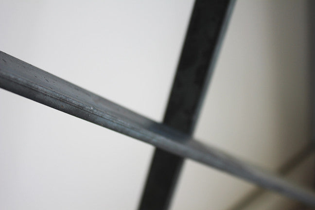 Close-up of the Live Edge console's crossed iron base, showing the metal joinery and finish